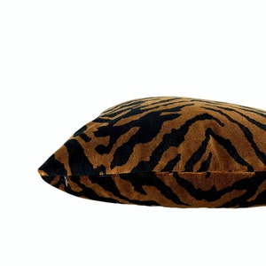 May include: A rectangular decorative pillow with a tiger stripe pattern. The pillow features a brown background with black stripes. The pillow is made of a soft, plush material and has a zipper closure.