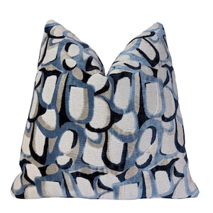 May include: Decorative throw pillow with a repeating abstract pattern in shades of blue, gray, and black. The pillow has a soft, textured appearance and is designed for home decor.