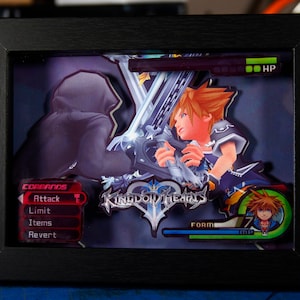 May include: A framed 3D artwork featuring characters from the video game Kingdom Hearts. The artwork includes Sora, Riku, and a command menu with options like Attack, Limit, Items, and Revert. The artwork is set against a dark blue background with a glowing blue and white effect.