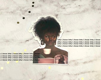 Puede incluir: Una pegatina que representa a una mujer de piel oscura y cabello rizado, sosteniendo una taza. La pegatina tiene el texto "Artsy L'Amour" repetido en los bordes. La mujer está representada con una taza en la mano, sobre un fondo de mármol.
