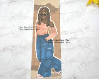 Puede incluir: Marcapáginas con una ilustración de una persona con un top rosa, pantalones cargo azules y gafas de sol. El fondo es de color beige con un patrón de cuadrícula. El marcapáginas tiene el texto "L'Amour" repetido.