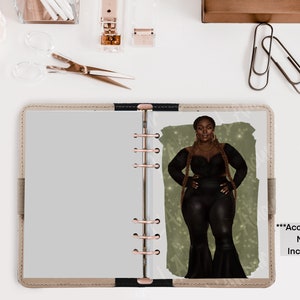 May include: A beige planner with a rose gold binding and a printed illustration of a woman in black attire. The illustration is set against a green backdrop. The text "Accessories NOT Included" is visible.