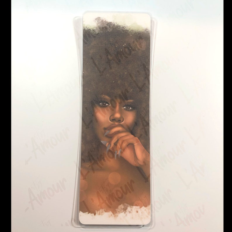 May include: A bookmark featuring a portrait of a woman with dark skin and curly brown hair. The woman is depicted with a thoughtful expression, her finger touching her lips. The bookmark has a clear plastic protective layer.