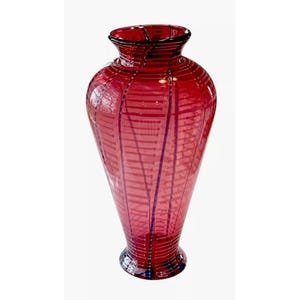 May include: A tall, red glass vase with a striped pattern. The vase has a wide base and a narrow neck.