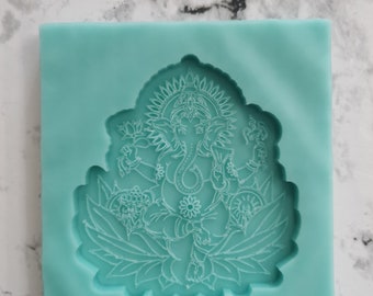 May include: A teal blue silicone mold with a detailed design of the Hindu deity Ganesha sitting on a lotus flower. The mold is designed for creating resin art or other crafts.