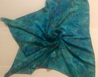 May include: A teal blue silk scarf with a marbled pattern. The pattern resembles feathers or leaves.