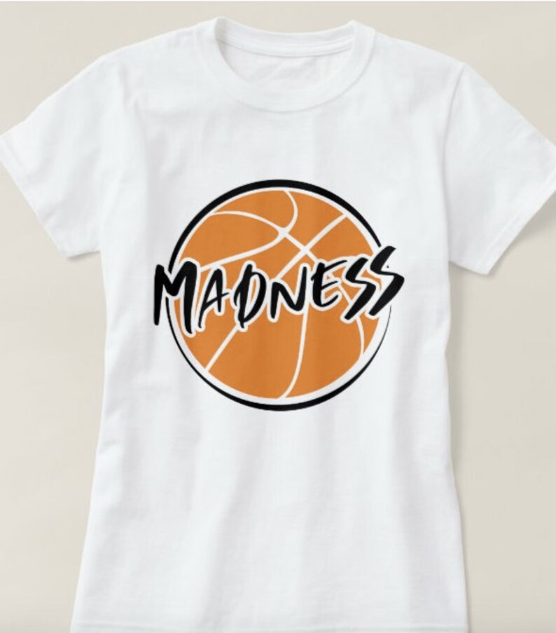 May include: White t-shirt with a black and orange basketball graphic and the word "MADNESS" written in black.