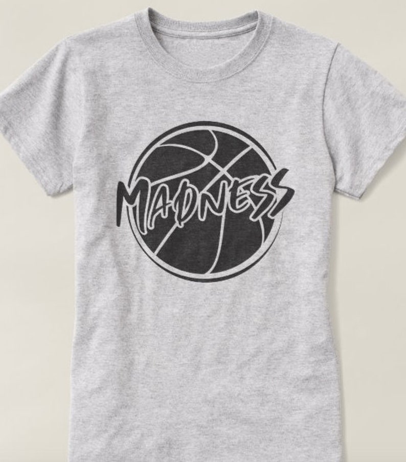 May include: Gray t-shirt with a black basketball graphic and the word "MADNESS" written in a stylized font.