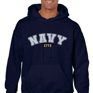 K&ouml;nnte beinhalten: Navyblauer Kapuzenpullover mit dem Wort "NAVY" in Wei&szlig; und dem Jahr "1775" in Gelb.