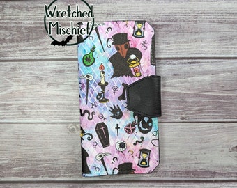 May include: A black and white phone case with a colorful design featuring a plague doctor, a skull, a coffin, and other spooky symbols. The text "Wretched Mischief" is visible in the top left corner.
