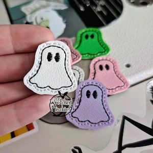 May include: Five felt ghost shapes in various colors, including white, green, pink, and purple. Each ghost has a black embroidered face with two eyes.