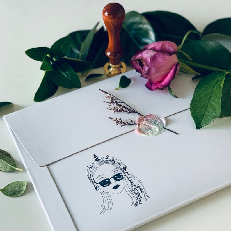 May include: A white envelope with a wax seal and a hand-drawn illustration of a person with a unicorn horn and sunglasses. The text "Nice to meet you" is written around the illustration.