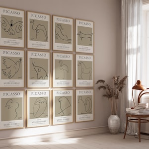 May include: A collection of framed Picasso art prints. Each print features a minimalist line drawing of an animal or figure against a neutral background. The prints are displayed on a light-colored wall, creating a gallery-like aesthetic.