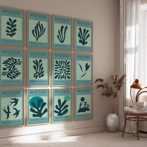 May include: A collection of framed art prints featuring abstract botanical designs in teal on a light green background. Each print is labeled "MATISSE" with additional text below. The prints are displayed on a light-colored wall.
