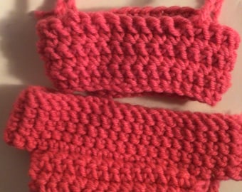 May include: A pink knitted bikini set for a doll. The top has thin straps and the bottom is a simple, high-waisted style.