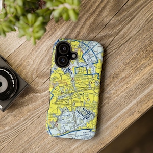 May include: A yellow and blue phone case featuring a detailed map design. The case has a camera cutout and is placed on a wooden surface. The map includes text such as "YORK", "SFC", and "NEW YORK".