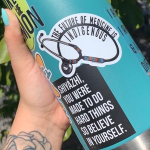 May include: A turquoise water bottle with a silver lid and a black and white sticker that says "The future of medicine is indigenous" with a stethoscope graphic. Another sticker says "Shiy&aacute;zhi, you were made to do hard things so believe in yourself."
