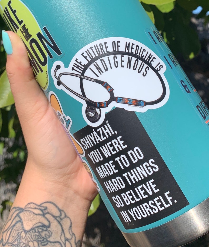 May include: A turquoise water bottle with a silver lid and a black and white sticker that says "The future of medicine is indigenous" with a stethoscope graphic. Another sticker says "Shiy&aacute;zhi, you were made to do hard things so believe in yourself."