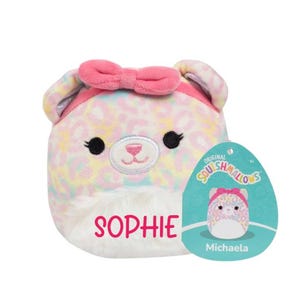 Peut inclure: Un jouet en peluche rose et blanc avec un motif l&eacute;opard et un n&oelig;ud rose. Le jouet a un visage blanc avec des yeux noirs et un nez rose. Le jouet est &eacute;tiquet&eacute; "Sophie" et porte une &eacute;tiquette indiquant "Original Squishmallows Michaela".