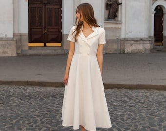Witte jurk van stofkostuum: elegante jurk met knoop aan de voorkant
