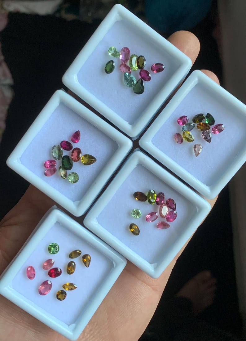 Puede incluir: Surtido de gemas de colores en peque&ntilde;as bandejas blancas. Las gemas var&iacute;an en forma y color, incluyendo rosa, verde, amarillo y marr&oacute;n. Las bandejas se sostienen en una mano.