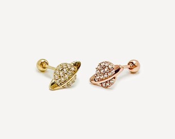 Puede incluir: Un par de pendientes de oro y oro rosa con un pequeño diseño de planeta brillante. Cada pendiente tiene un pequeño tachón redondo.