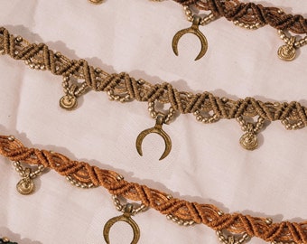 May include: Three layered necklaces with brown and green cord, gold beads, and crescent moon charms.