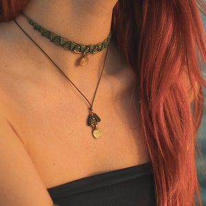 May include: A woman wearing a green macrame choker necklace with a gold pendant and a matching longer necklace with a gold pendant.