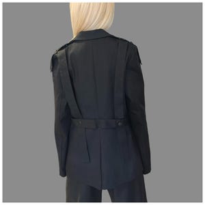 Designer black women’s blazer in denim with modern avant-garde construction and decorative straps.