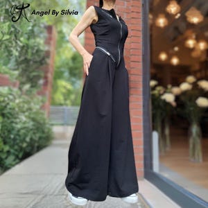 May include: Black sleeveless jumpsuit with a silver zip and wide-leg trousers. The jumpsuit features a high neckline and pockets. The brand name "Angel By Silvia" is visible in the upper left corner.