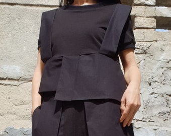 May include: A black layered top with a unique design featuring a folded panel at the waist. The top has a relaxed fit and short sleeves.