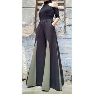 May include: Wide-leg pants with a black and olive green color block design. The pants have a high waist and a relaxed fit.