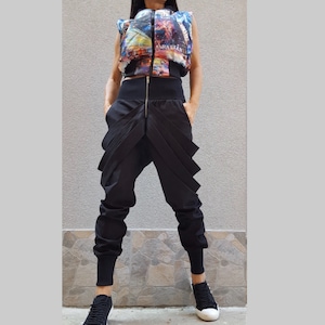 May include: Black pants with a unique, layered design and a zipper detail. The pants have a relaxed fit and a cuffed hem.
