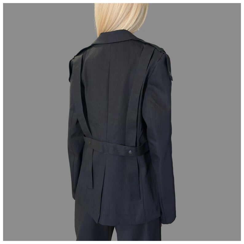 Black tailored avant-garde jacket for women with decorative asymmetric straps and modern statement design.