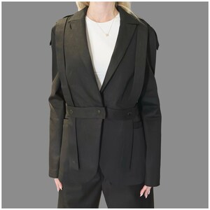 Black avant-garde denim blazer with asymmetric straps and eyelet details, tailored women’s designer jacket shown from the front.