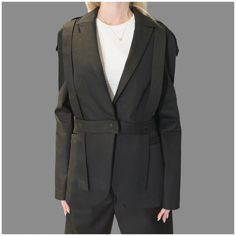 Black avant-garde denim blazer with asymmetric straps and eyelet details, tailored women’s designer jacket shown from the front.