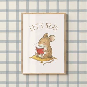 May include: A framed print featuring a charming illustration of a brown mouse reading a red book while seated on a yellow cushion. The words "LET'S READ" are written above the mouse in brown lettering. The background is a blue and white plaid pattern.