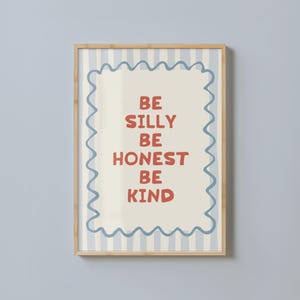 Puede incluir: Un cartel enmarcado con las palabras "BE SILLY BE HONEST BE KIND" en letras rojas. El cartel tiene un fondo crema con un borde ondulado azul y un fondo a rayas azul claro.