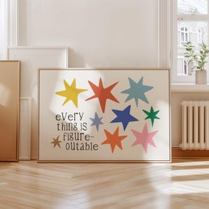 May include: A framed art print featuring colorful star shapes in yellow, red, blue, green, orange, and pink. The print includes the text "Every thing is figure-outable" in a playful font, set against a cream background. The frame is a light wood color.