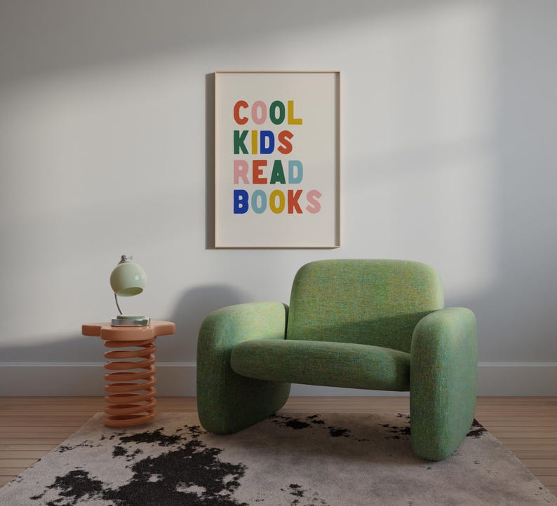 May include: A green armchair with a colorful framed print that reads "COOL KIDS READ BOOKS" hanging on the wall behind it. A small wooden side table with a spring base sits in front of the chair.