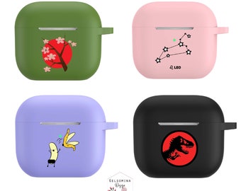Peut inclure: Quatre étuis AirPod différents avec des designs variés. Le premier étui est vert avec un soleil rouge et des fleurs de cerisier roses. Le deuxième étui est rose avec une constellation et le texte "Ω LEO". Le troisième étui est violet avec une banane et une banane pelée. Le quatrième étui est noir avec un cercle rouge et une silhouette de dinosaure.