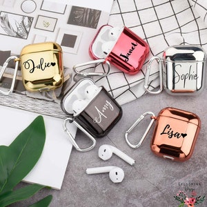 May include: Five personalised Airpod cases in different colours. The cases are gold, red, silver, black, and rose gold. Each case has a name on it: Julie, Janet, Sophie, Amy, and Lisa.