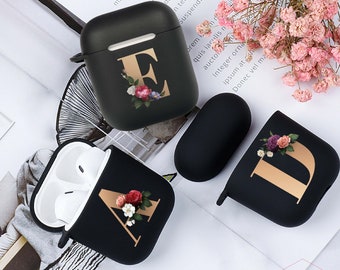 May include: Three black Airpod cases with floral designs and gold letters. The letters are A, D, and E.