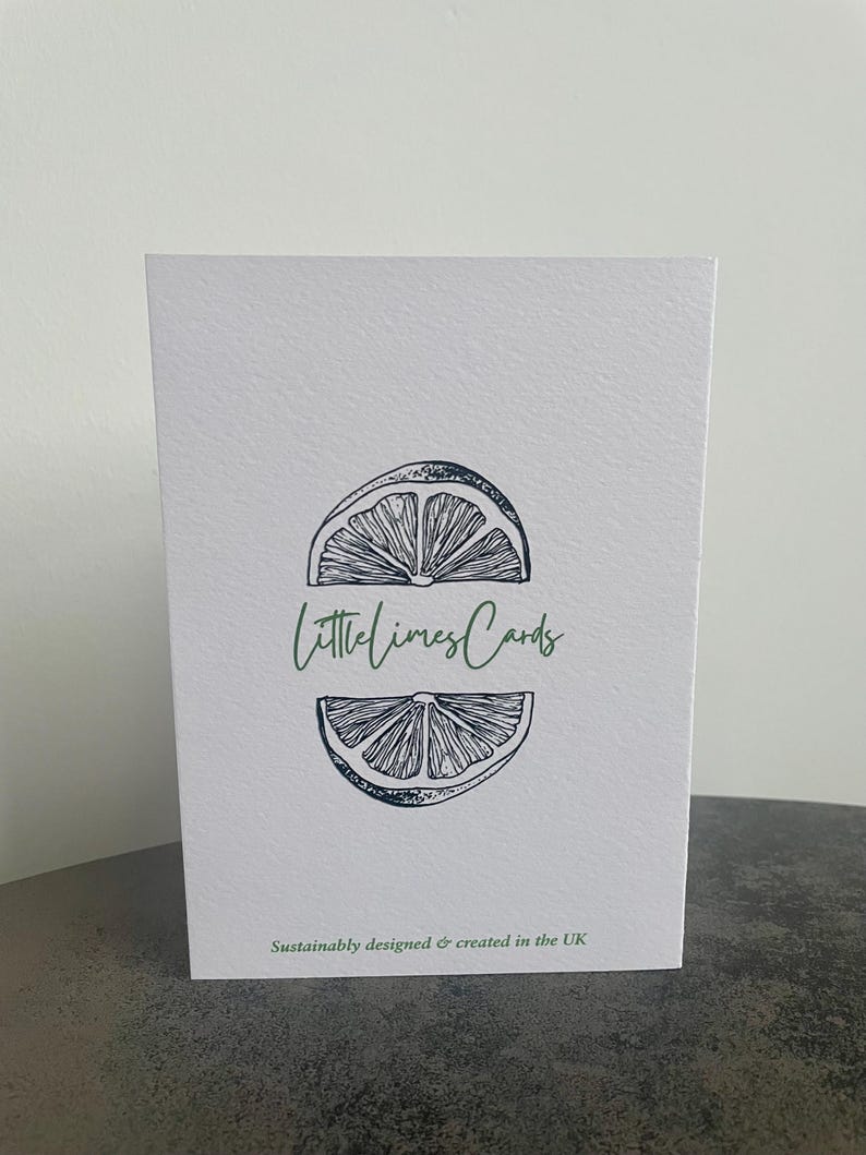 May include: A white card with a black and white illustration of a lime wedge. The text "littlelimesCards" is written in green letters on the card. The text "Sustainably designed & created in the UK" is written in black letters at the bottom of the card.