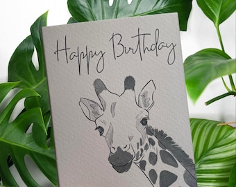 May include: A gray and white birthday card with the text "Happy Birthday" and a black and white illustration of a giraffe's head.