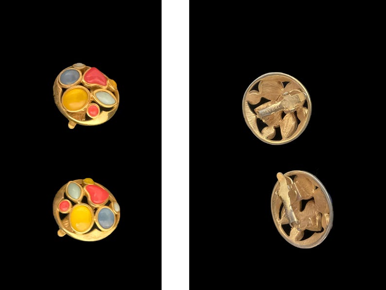 May include: A pair of gold-tone earrings with colorful enamel accents. The earrings feature a round design with a cluster of red, yellow, blue, and white enamel stones. The backs of the earrings are also gold-tone and feature a decorative design.