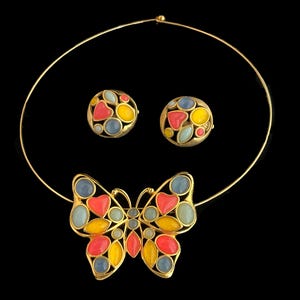 May include: A gold necklace with a butterfly pendant. The butterfly is made of gold and has red, yellow, blue, and green enamel. The necklace also comes with a pair of matching earrings.