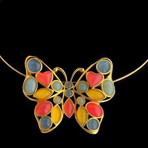May include: A gold butterfly necklace with colorful stones. The butterfly has blue, red, and yellow stones.