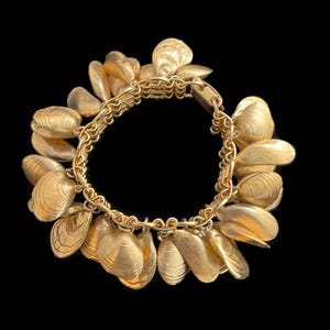 May include: A gold-tone bracelet with a chain link design and multiple dangling charms shaped like seashells.