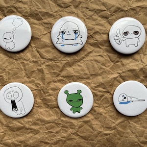 Peut inclure: Ensemble de six badges ronds blancs avec des illustrations de dessins animés. Les motifs comprennent un personnage avec une bulle de pensée, un personnage qui pleure, un personnage qui lève le pouce, un personnage qui crie, un extraterrestre vert et un personnage allongé.
